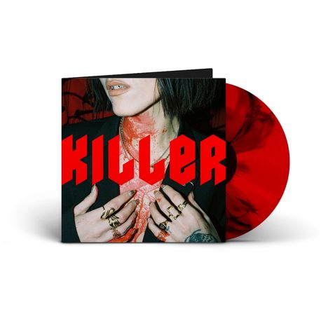 "KILLER" in großen roten Buchstaben. Nahaufnahme eines Gesichts mit kurzen Haaren, viele Ringe an den Händen.