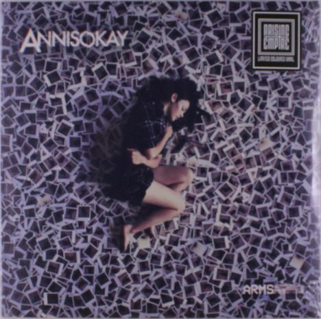 Text: "ANNISOKAY", "Arising Empire", "Arms". Eine Person liegt auf einem Haufen von Polaroidfotos.