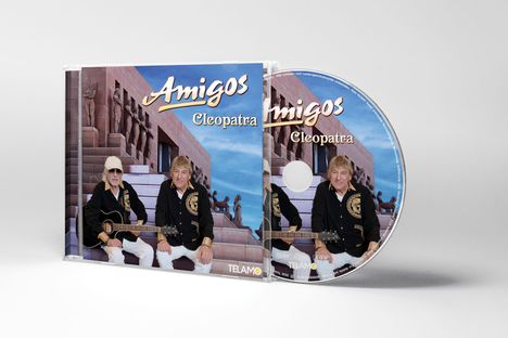 „Amigos - Cleopatra“ steht in goldener Schrift. Zwei Männer sitzen vor einem ägyptischen Gebäude. Sie tragen schwarze Hemden.