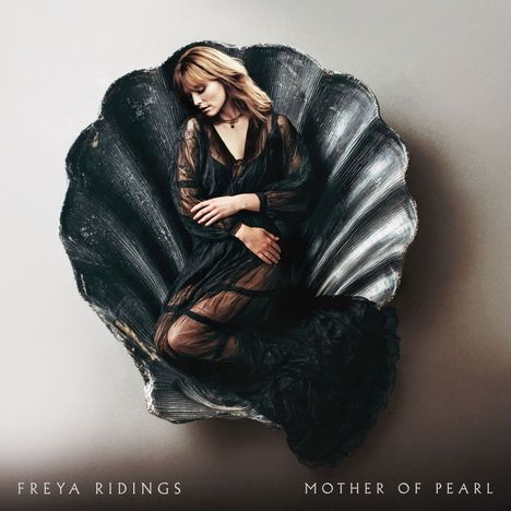 "FREYA RIDINGS MOTHER OF PEARL" steht unten. Eine Frau in schwarzem Kleid ruht in einer großen Muschelschale.