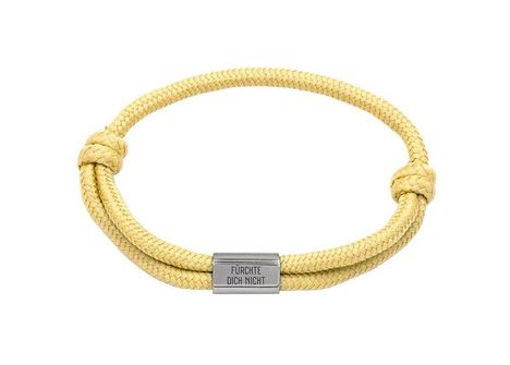 "FÜRCHTE DICH NICHT" steht auf einer Metallplatte. Es ist ein gelbes geflochtenes Seilarmband mit Knoten.
