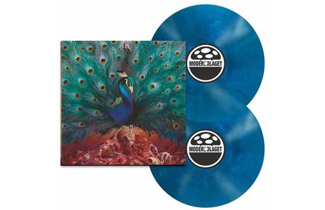 Text: "Modern Lager" auf zwei Schallplatten. Ein Gemälde zeigt einen Pfau mit ausgebreitetem Gefieder auf einem Schädelhaufen.