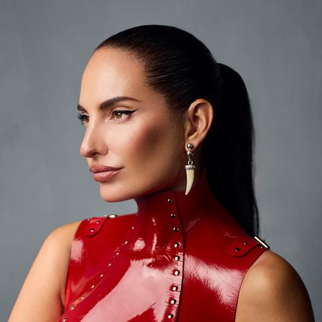 Ich kenne keine Texte oder bedeutenden Markierungen hier. Leicht gebräunte Person mit glattem, langem Haar und rotem Outfit mit Nieten.