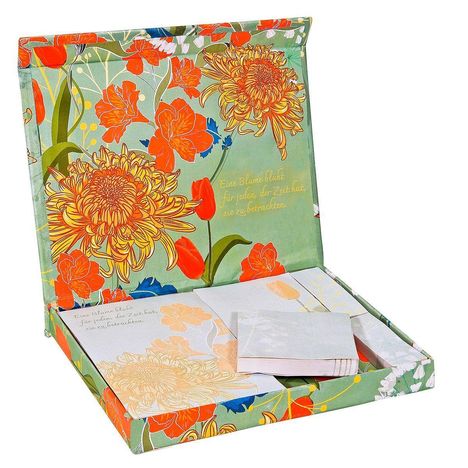 Eine bunte Box mit Blumenmuster, darin Notizblöcke. Text: "Eine Blume blüht für jeden, der Zeit hat, sie zu betrachten."