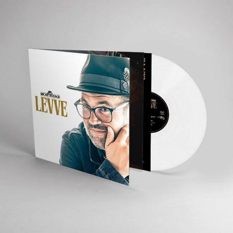 Text: "ECHTEELSICHE LEVVE". Ein Mann mit Brille und Hut, die Hand am Kinn, auf einem Schallplattencover mit weißer Platte.