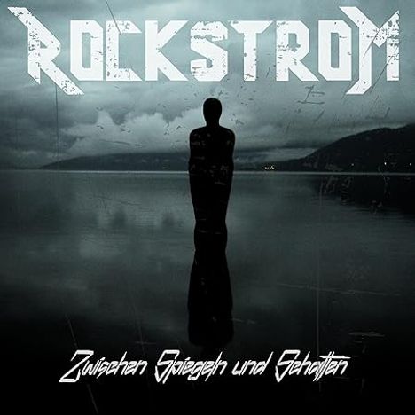 "ROCKSTROM" oben in großer Schrift, "Zwischen Spiegeln und Schatten" unten. Dunkle Figur am Wasser, neblige Atmosphäre.