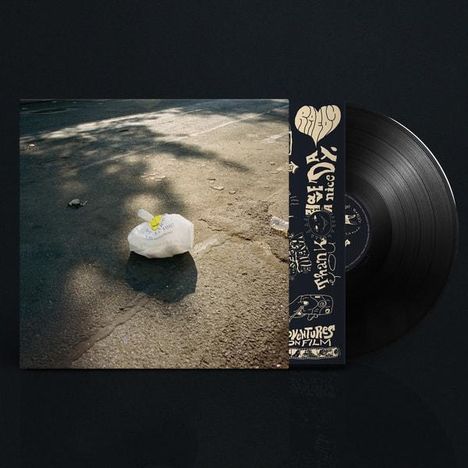 „The Velvet Underground & Nico“. Schwarze Vinyl-Schallplatte liegt neben einem Albumcover mit Plastiktüte auf Asphalt.