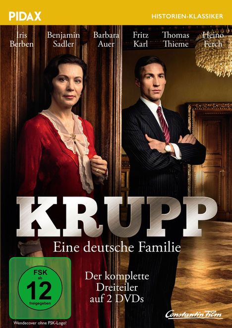 „KRUPP - Eine deutsche Familie.“ Zwei Personen in formeller Kleidung, stehen in einem eleganten Raum.