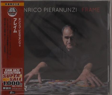 Aufschrift: "ENRICO PIERANUNZI FRAME". Ein Mann berührt etwas auf einem Tisch, in einem dunklen Raum.