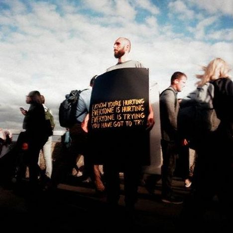 Menschenmenge, eine Person trägt ein Schild: "I know you're hurting, everyone is hurting, everyone is trying, you have got to try".