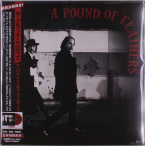 "A Pound of Feathers", zwei Männer in Schwarz-Weiß, der eine trägt einen Hut, in urbaner Umgebung.