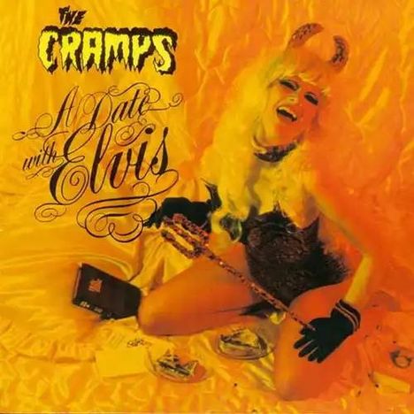 „The Cramps“, „A Date with Elvis“. Eine Person mit blonder Perücke, Hörnern, in glamourösem Outfit auf orangem Hintergrund.