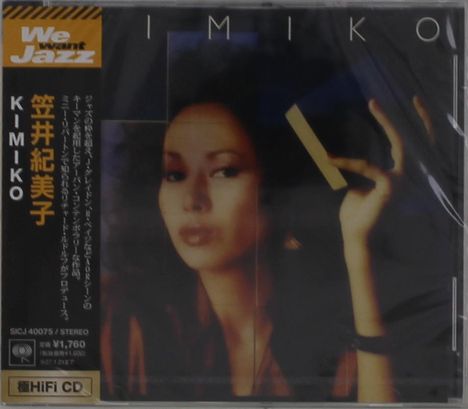 We want Jazz, KIMIKO. Eine Frau hält einen gelben Fächer, ihr Gesicht ist ernst und nachdenklich.