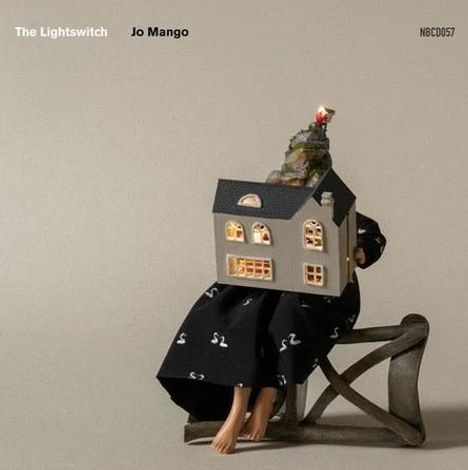Text: „The Lightswitch“, „Jo Mango“, „NBCD057“. Eine Figur in schwarzem Gewand hält ein beleuchtetes Modellhaus.