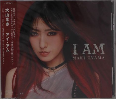 Die Texte "I AM" und "MAKI OYAMA" sind prominent. Eine Frau mit roten Haaren und dunkler Kleidung ist abgebildet.