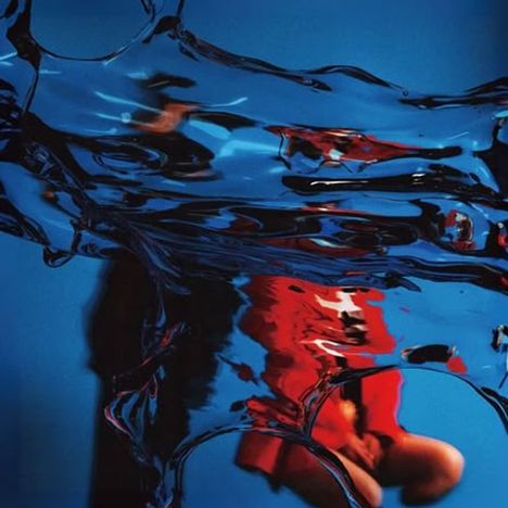 Kein Text vorhanden. Eine verschwommene Szene mit blauen und roten Farben, die durch Wasser verzerrt erscheinen.