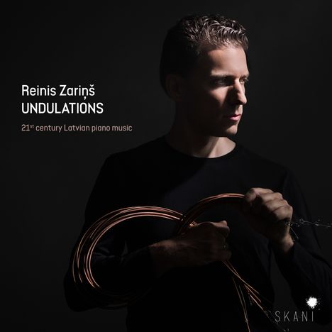 Reinis Zariņš, UNDULATIONS, 21st century Latvian piano music. Ein Mann in dunkler Kleidung hält Kabel in den Händen.