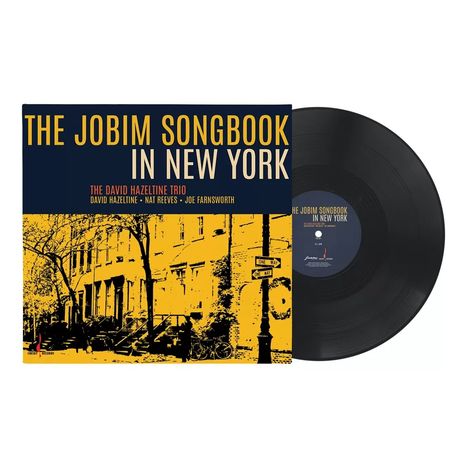"THE JOBIM SONGBOOK IN NEW YORK" in großen Buchstaben. Darunter "THE DAVID HAZELTINE TRIO" auf einem Albumcover.