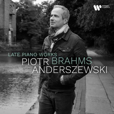 „Late Piano Works Piotr Brahms Anderszewski“. Ein Mann in einer Jacke steht am Wasserweg, links ein Gebäude.