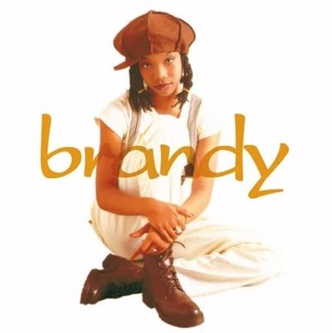 Text: "brandy" in gelber, verspielter Schrift. Eine Frau sitzt entspannt, trägt braune Kleidung und schaut freundlich.