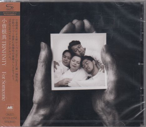 Texte in japanischen Schriftzeichen und "TRINFINITY For Someone". Schwarz-weißes Foto von vier Menschen in einem Paar Händen gehalten.