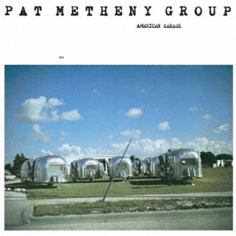 "PAT METHENY GROUP AMERICAN GARAGE." Eine Wiese mit glänzenden Wohnwagen unter blauem Himmel.