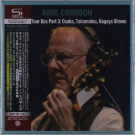 KING CRIMSON, Tour Box Part 3: Osaka, Takamatsu, Nagoya Shows. Ein Musiker trägt Kopfhörer und hält ein Instrument.