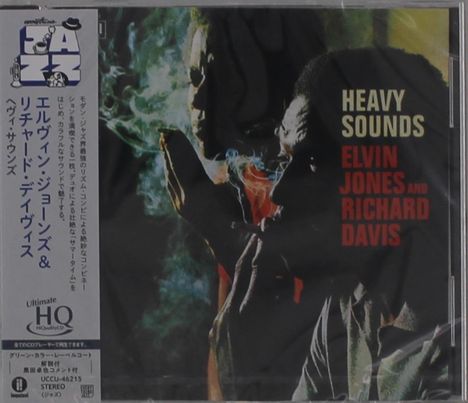 "HEAVY SOUNDS" steht in weißer und roter Schrift. Zwei Menschen, einer raucht, in gedämpftem Licht. Jazz-Atmosphäre.