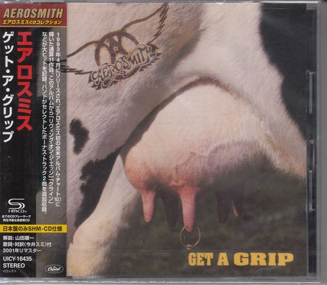 Japanische Texte links, "GET A GRIP" unten rechts. Eine Kuh mit einem Ring im Euter, darüber ein Logo.