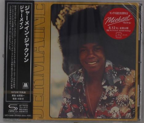 "Jermaine Jackson" und japanische Schriftzeichen. Ein lächelnder Mann in bunter Kleidung und Afrofrisur.