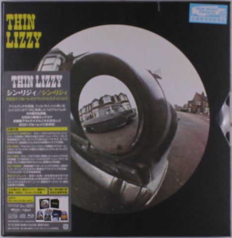 "THIN LIZZY" oben links in gelb, daneben in einem Kreis ein Auto in einer Straßenszene. Japanische Texte unten links.