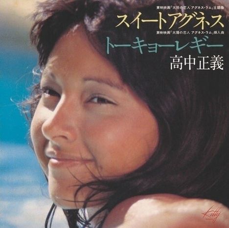 Japanische Schrift auf blauem Hintergrund. Nahaufnahme einer lächelnden Frau mit dunklen Haaren und blauem Himmel.