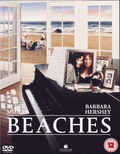 "Bette Midler", "Barbara Hershey", "BEACHES". Ein Klavier mit Fotos, eine Strandlandschaft und zwei Frauen am Strand.