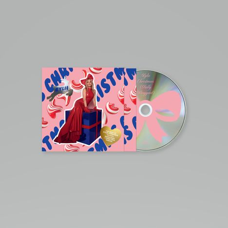 Kylie Christmas (Fully Wrapped). Best of Kylie Christmas; 22 Tracks. Frau in Rot sitzt auf Geschenk, Hintergrund rosa.