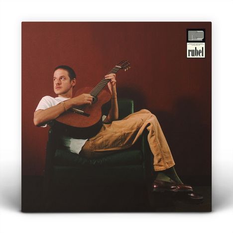 Oben steht "rubel" neben einem abstrakten Logo. Ein Mann sitzt auf einem Stuhl, Gitarre in den Händen.