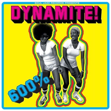 "DYNAMITE!" oben in großer Schrift, darunter "600%". Zwei Frauen in sportlicher Kleidung tanzen fröhlich.