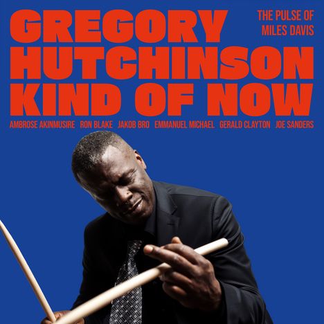 "GREGORY HUTCHINSON KIND OF NOW" in großen, orangen Buchstaben vor blauem Hintergrund. Mann mit Schlagzeugstöcken.