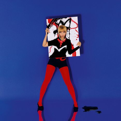 Person hält ein Gemälde, trägt rot-schwarze Kleidung, steht vor blauem Hintergrund. Gesicht im Ausschnitt des Gemäldes.