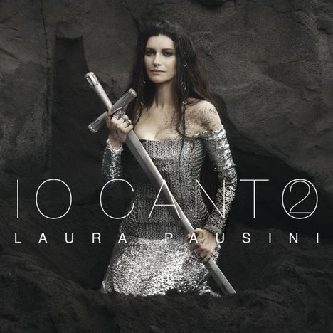 Text: "IO CANTO" und "LAURA PAUSINI". Eine Frau in silbernem Kleid hält ein Schwert, umgeben von dunklem Sand.