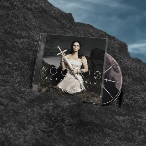 CD-Hülle mit "YO CANTO LAURA PAUSINI", Frau im weißen Kleid auf Felsen, hält ein silbernes Schwert, CD daneben.