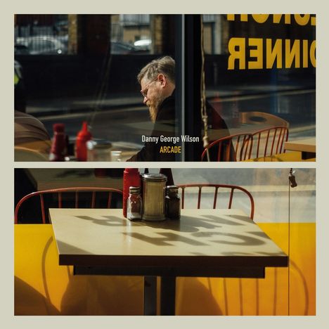Texte: Danny George Wilson, ARCADE.  
Ein Mann mit Bart sitzt in einem Café. Ein leerer Tisch mit Gewürzen.