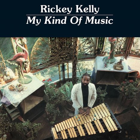 "Rickey Kelly My Kind Of Music". Ein Mann steht an einem Xylophon in einem Zimmer mit Pflanzen und künstlerischen Details.