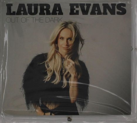 Text: "LAURA EVANS OUT OF THE DARK". Eine blondhaarige Frau schaut lächelnd mit einer Hand am Kinn nach vorne.