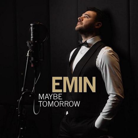 Text: "EMIN MAYBE TOMORROW". Ein Mann im Anzug steht mit verschränkten Armen neben einem Mikrofon.