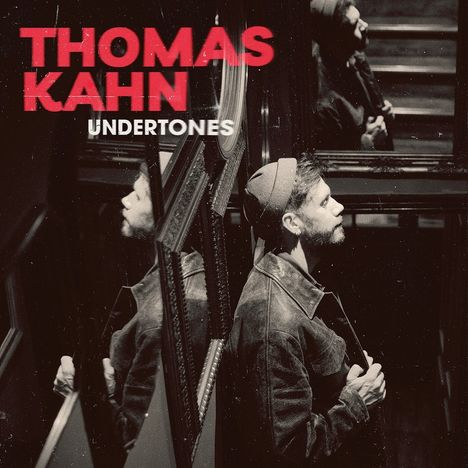 "THOMAS KAHN UNDERSONES" in roten und weißen Buchstaben, zeigt einen Mann in einem Treppenhaus mit Spiegeln.