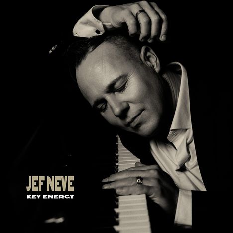 Text: "JEF NEVE - KEY ENERGY". Ein Mann lehnt sich entspannt mit geschlossenen Augen an ein Klavier. Schwarz-Weiß-Foto.