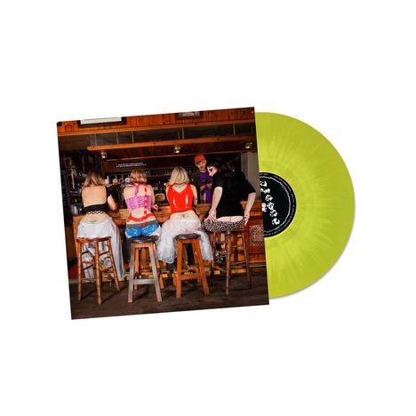 Personen sitzen in bunter Kleidung auf Barhockern. Eine gelbe Vinyl-Schallplatte liegt daneben.