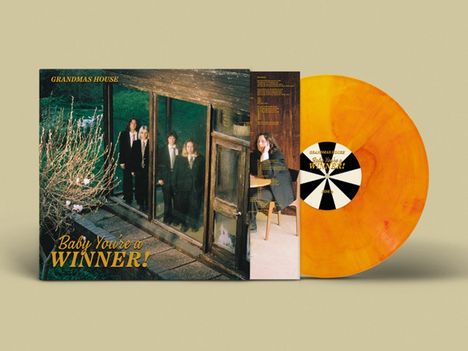 "Baby You're a WINNER!" auf einem gelben Hintergrund. Schallplatte ist orange. Vier Personen in einem Haus.