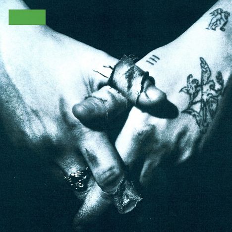 Grüne Fläche oben links; Hände mit Tattoos und zwei Fingern mit Bandagen.