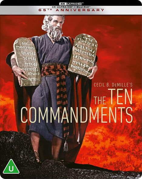 "Cecil B. DeMille's The Ten Commandments. Ein Mann in antiker Kleidung hält zwei Tafeln vor einem feurigen Hintergrund."